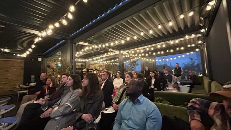 Audience seated under string lights at The Conduit in London, attending Musana’s Aid v Enterprise event focused on sustainable development and social enterprise in Uganda.